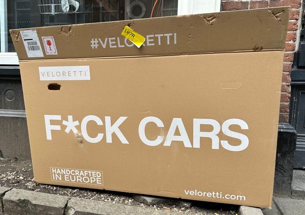 large empty carboard box that held unassembled bicycle with f*ck cars written on side